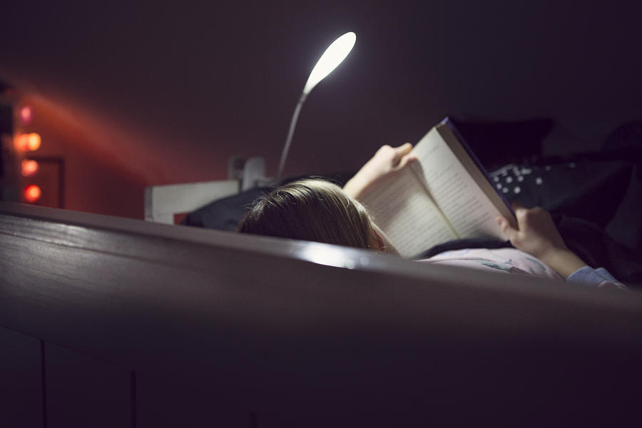 Child reading bedtime book lit by night light Photograph by Elva Etienne