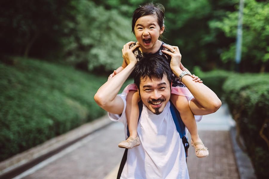 Child riding on dads shoulders joyfully in park Photograph by Images By Tang Ming Tung