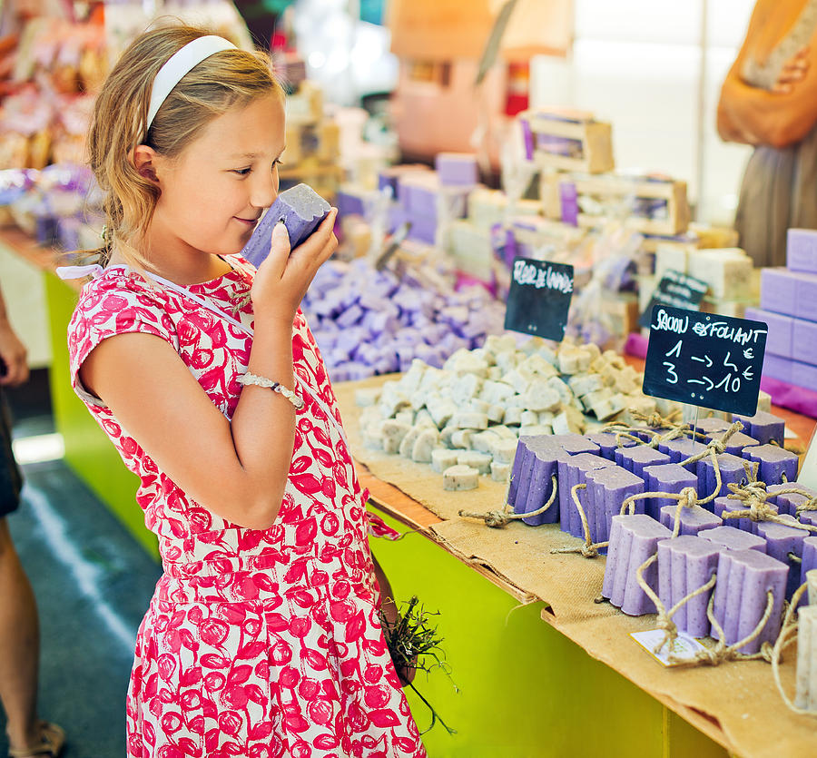 Child sniffing soap at a farmers market in Provenve Photograph by ArtMarie