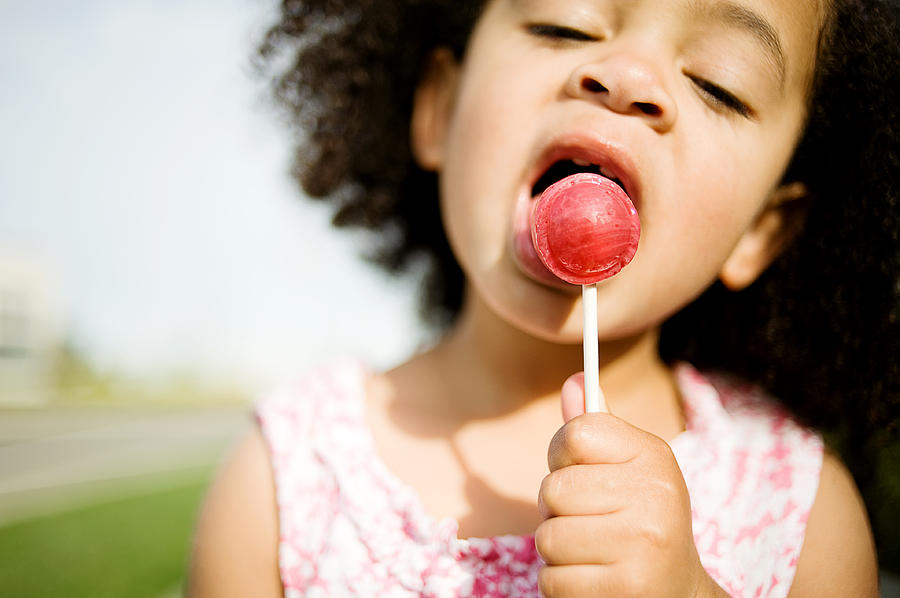 Child with Afro licking red lollipop Photograph by Diyosa Carter