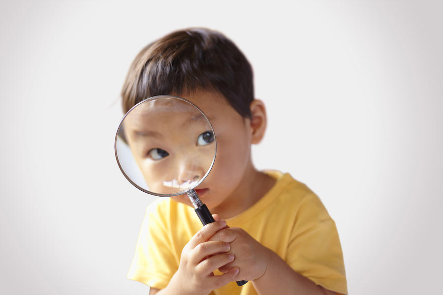 Children looking into a magnifying glass Photograph by Sudo Takeshi