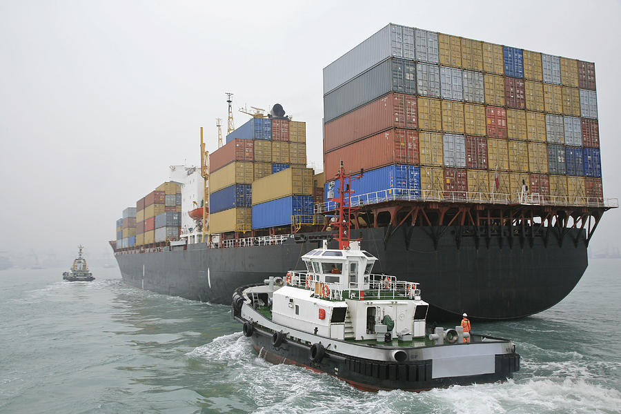 China, Hong Kong Harbor, tugboat sailing alongside container ship Photograph by Kevin Phillips