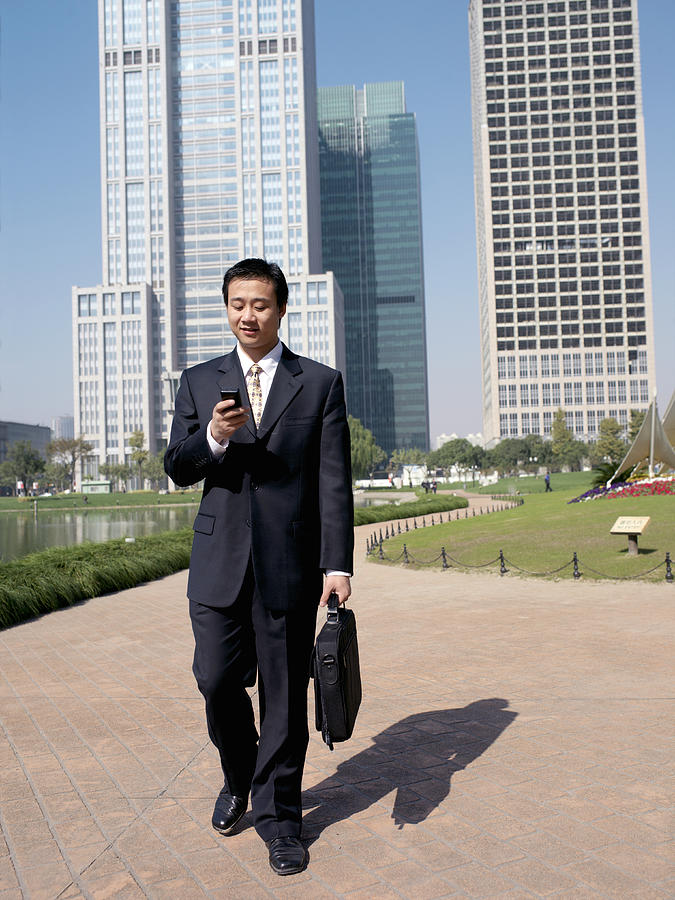 Chinese businessman text messaging near office buildings Photograph by xPACIFICA