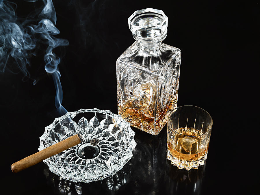 Cigar in ashtray with decanter and tumbler of whiskey Photograph by Image Source