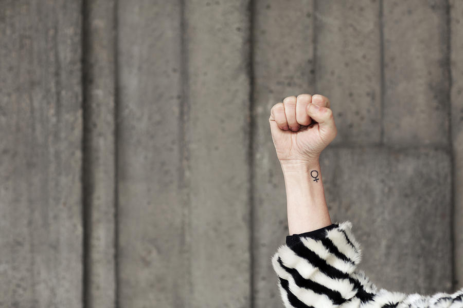 Clenched fist and female symbol on arm Photograph by Johner Images