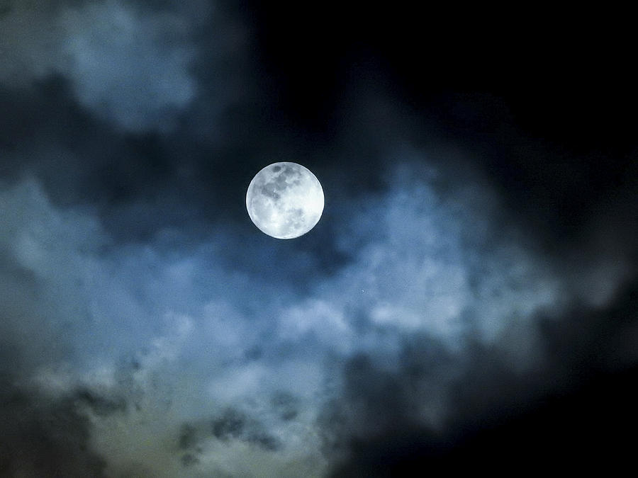 Close up detail of a full moon shining through bluish clouds Photograph by Ashley