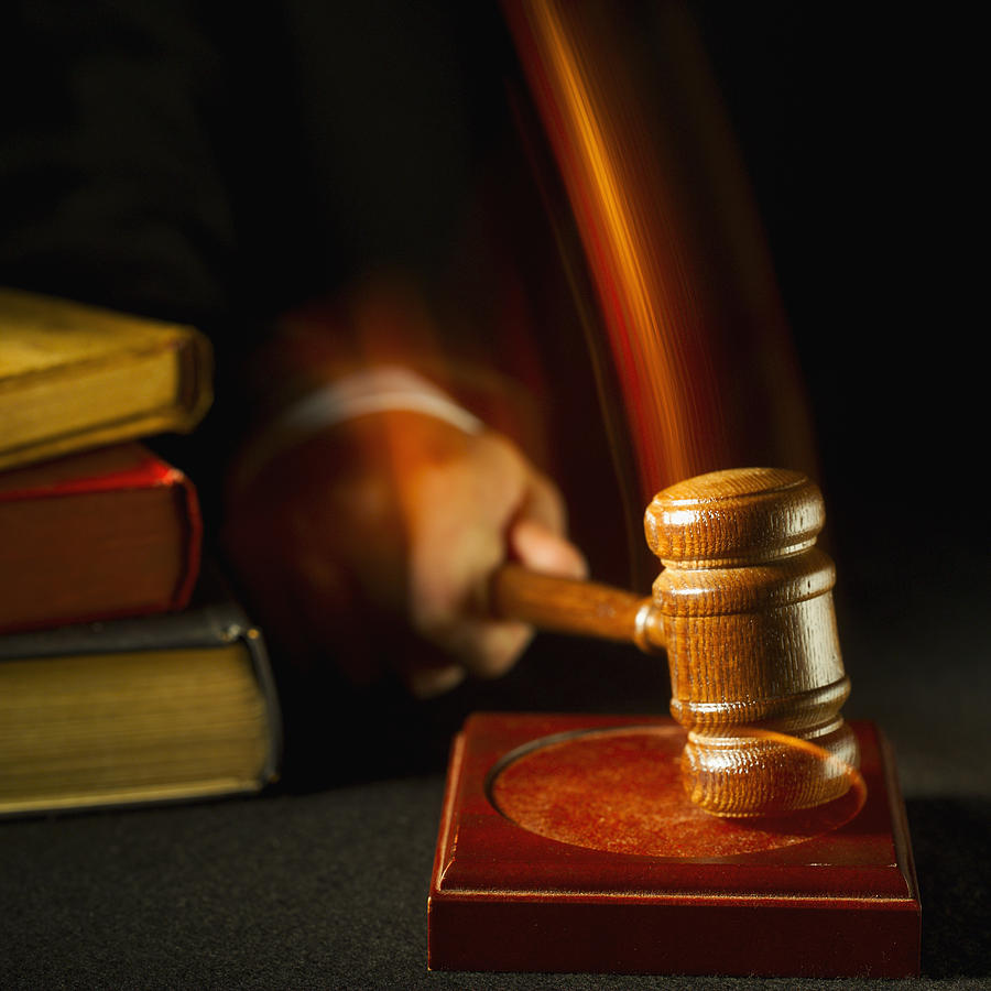 Close-up mid section of judge hitting gavel on pad Photograph by Stockbyte