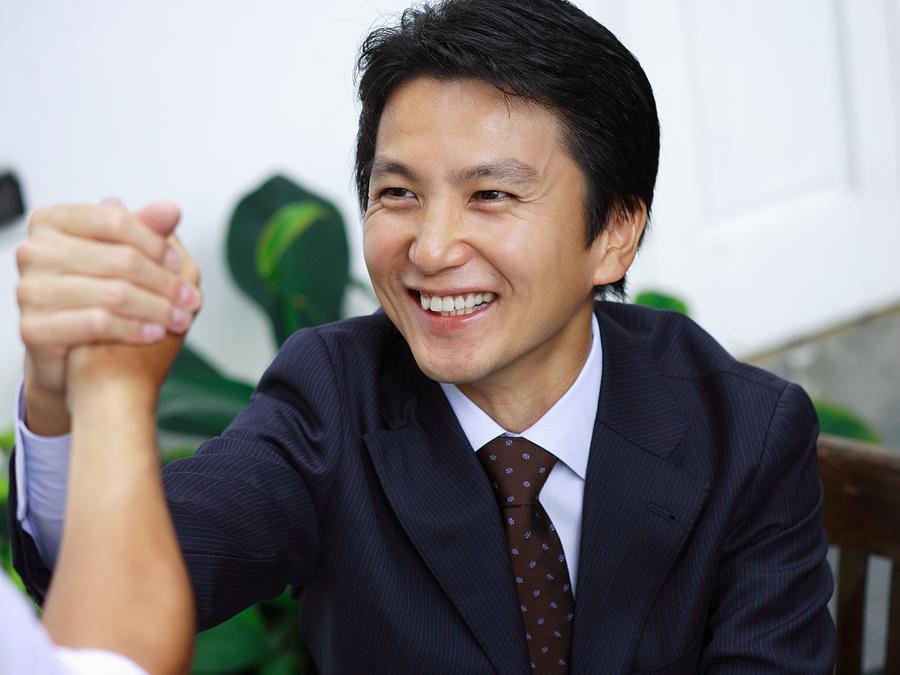 Close-up of a businessman shaking his hand with another businessman Photograph by Meg Takamura