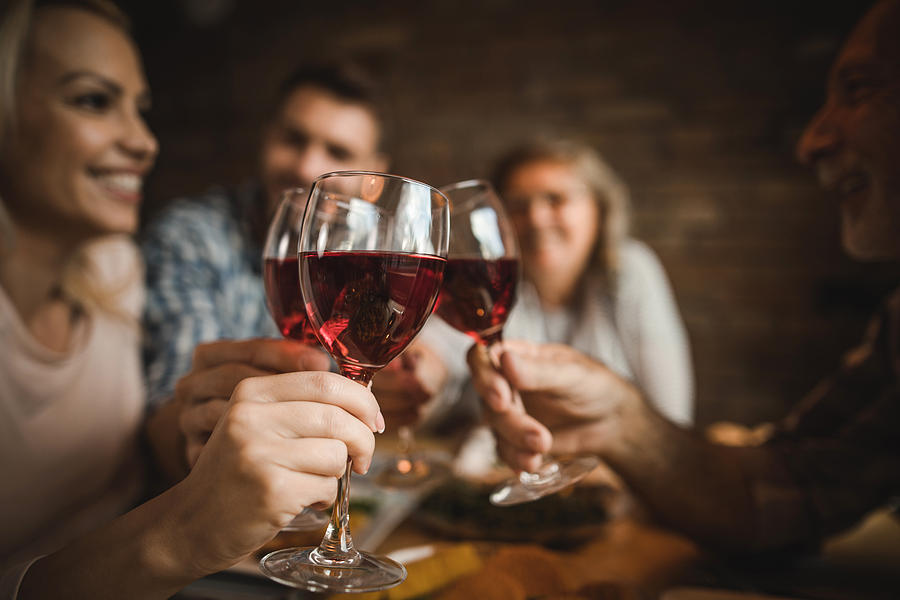 Close up of a family toasting with red wine at home. Photograph by Skynesher