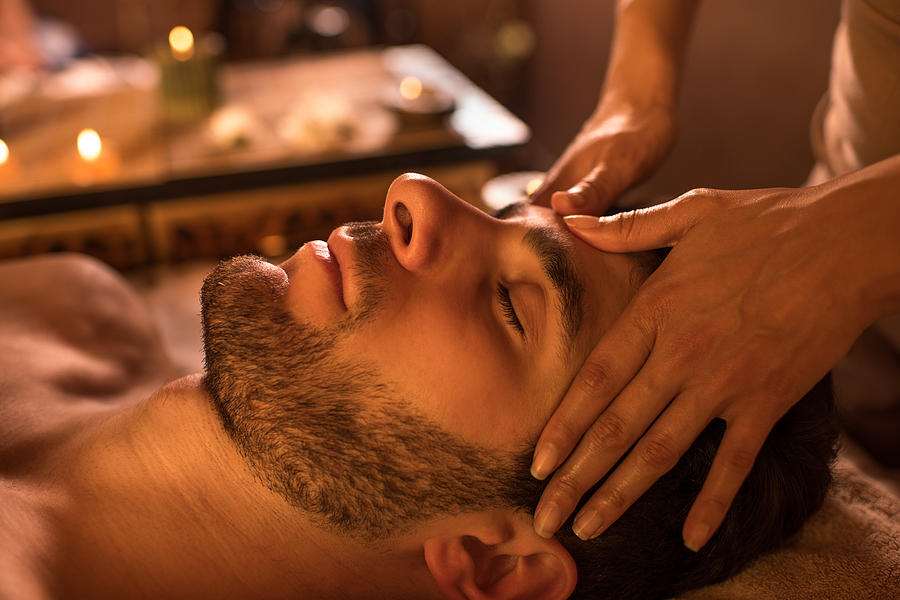 Close-up of a man receiving facial massage at the spa. Photograph by Skynesher