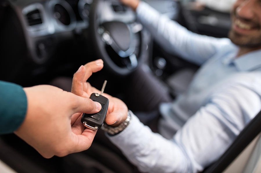 Close up of a man receiving new car key. Photograph by Skynesher