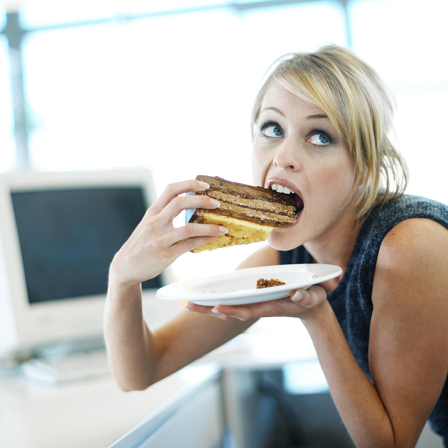 Close-up Of A Woman Eating A Large Piece Of Cake Photograph by Stockbyte