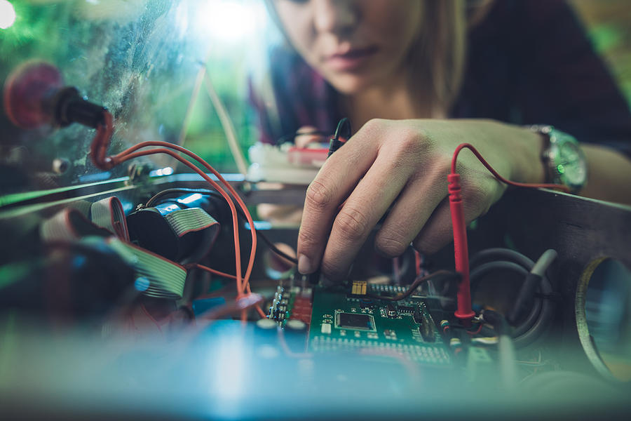 Close up of a woman repairing electrical component of a computer. Photograph by Skynesher