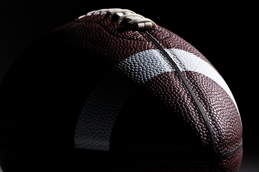 Close-up of American football with dramatic lighting Photograph by Kledge