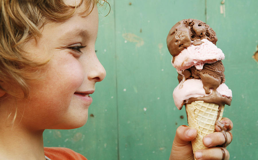 Close up of boy (6-7) holding ice cream cone, side view Photograph by David Malan