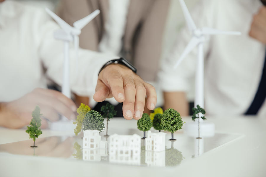 Close-up of business people wind turbine model and houses on conference table Photograph by Westend61
