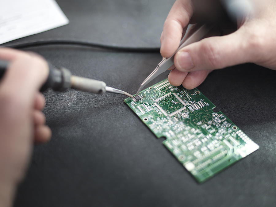 Close up of engineer soldering prototype circuit board Photograph by Monty Rakusen