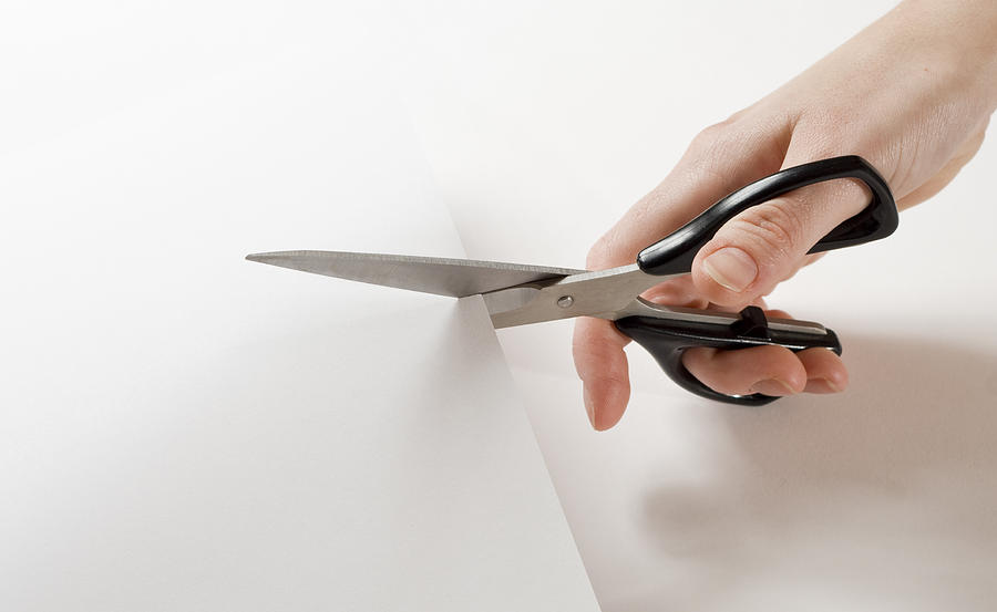 Close up of hand holding scissors and cutting through paper Photograph by Wega52