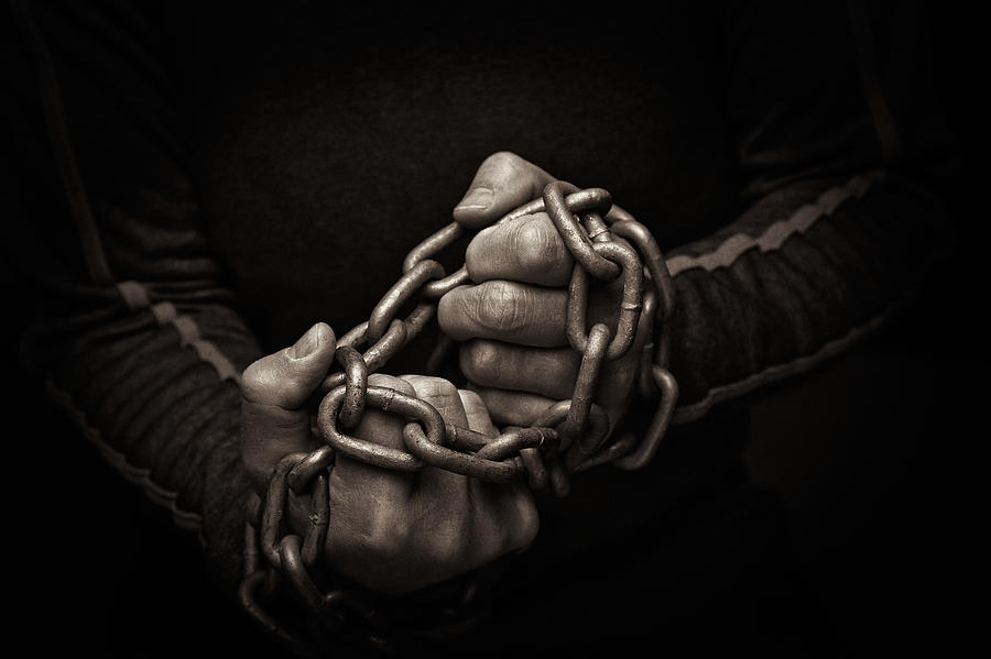 Close-up of hands trying to break chains Photograph by Stevepamp