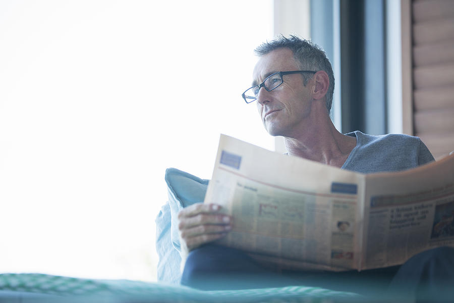 Close up of man reading newspaper in living room Photograph by David Lees