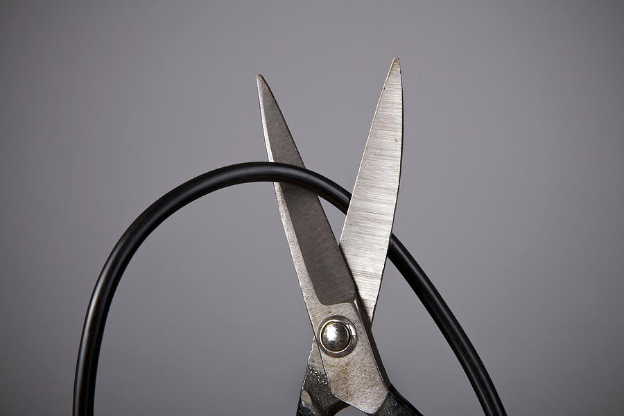 Close up of metal scissors cutting black wire Photograph by GoodLifeStudio
