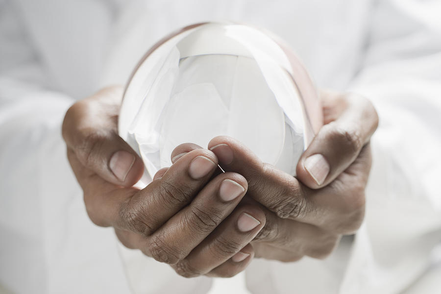 Close up of mixed race man holding crystal ball Photograph by REB Images