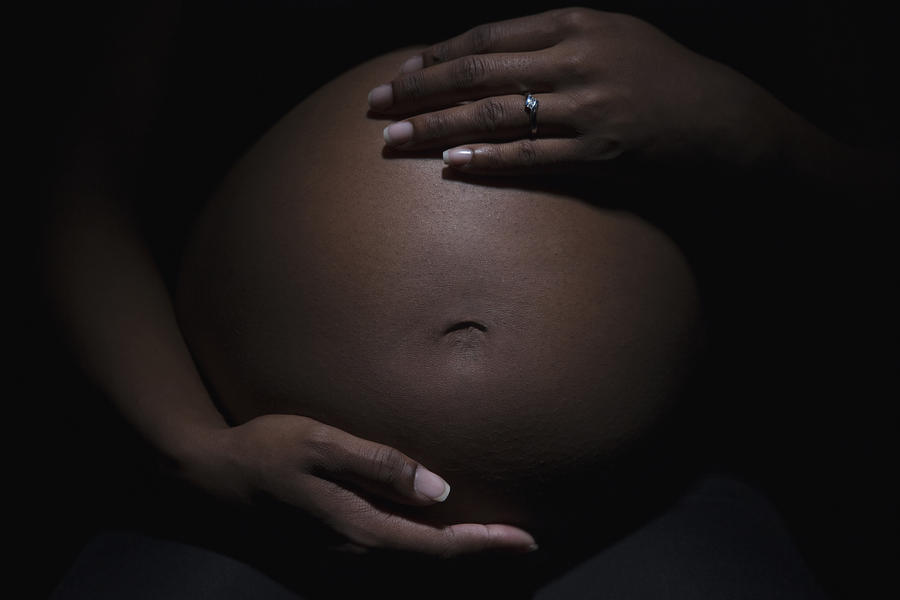 Close up of mixed race womans pregnant stomach Photograph by Jose Luis Pelaez Inc