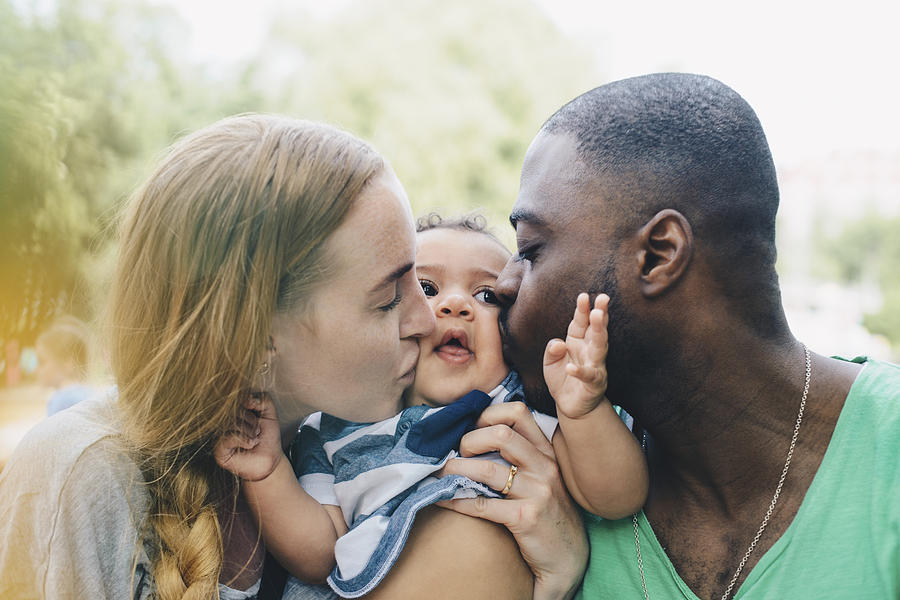 Close-up of multi-ethnic parents kissing son Photograph by Maskot