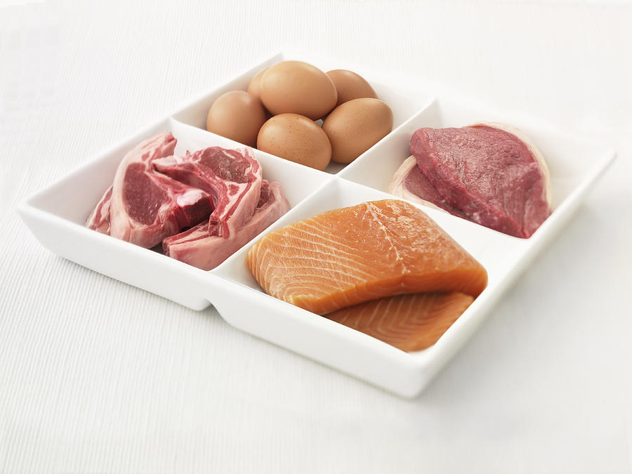 Close up of sectioned plate with eggs, pork, salmon and steak Photograph by Adam Gault
