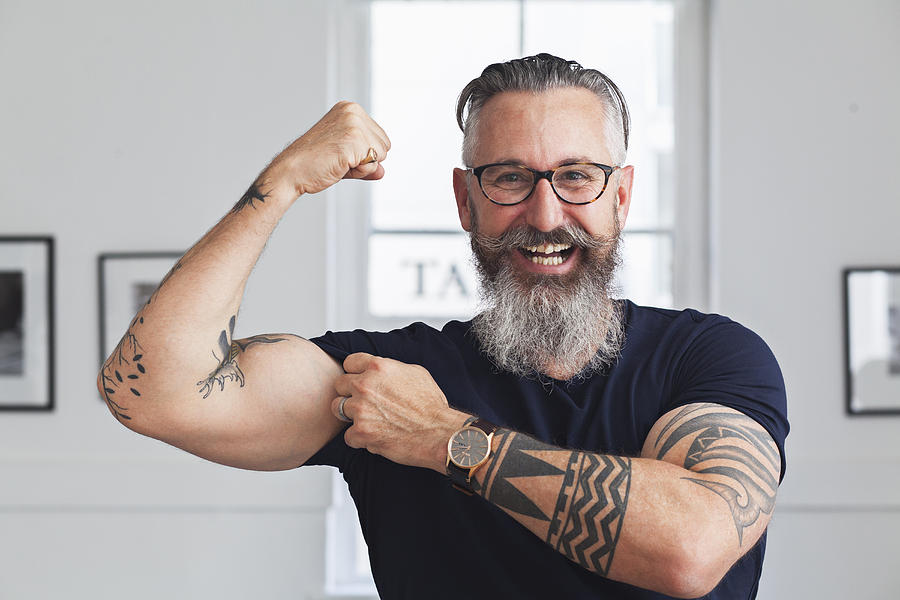 Close up of smiling muscular Caucasian hipster man flexing biceps Photograph by Strauss/Curtis