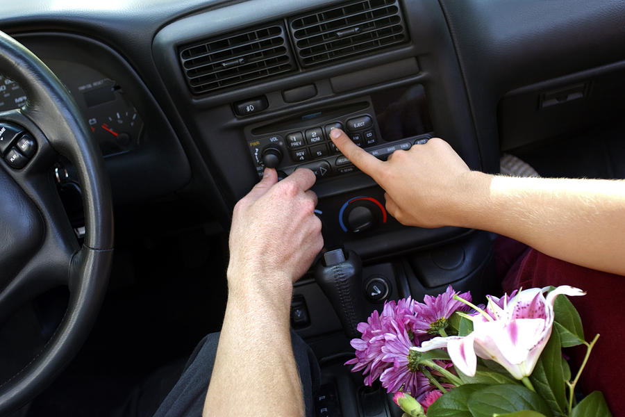 Close-up of two hands pressing buttons to adjust the car stereo. Photograph by Thinkstock