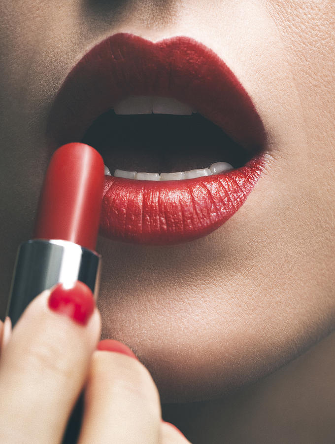 Close up of woman applying red lipstick Photograph by Lumina Images