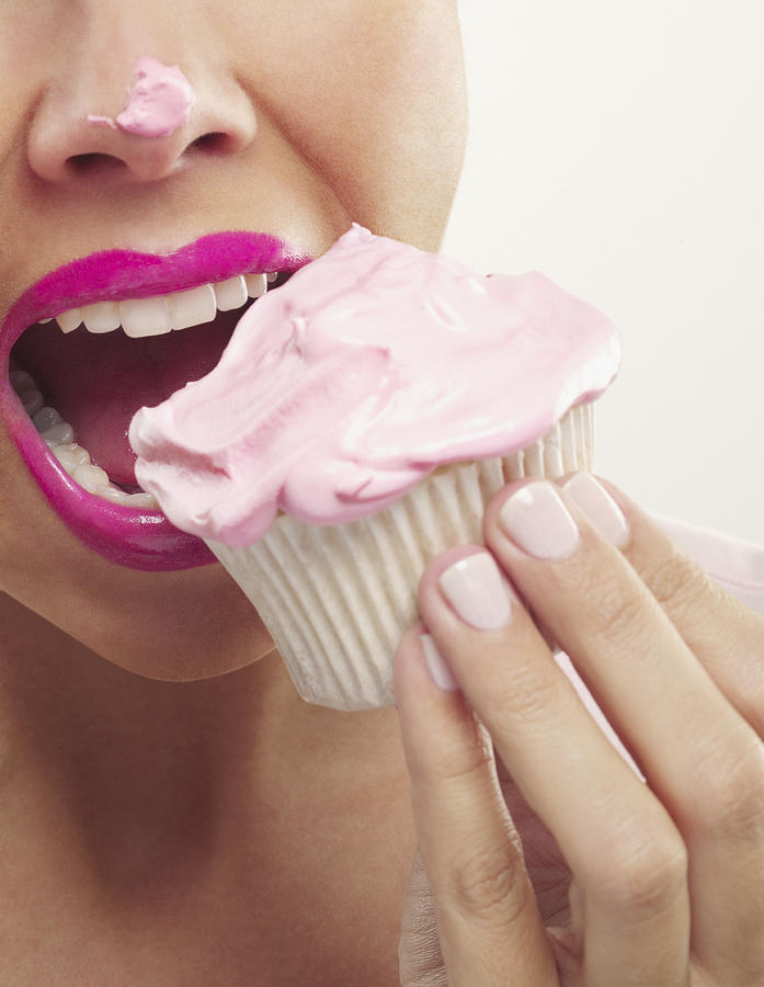 Close up of woman with pink lipstick and frosting on nose eating cupcake Photograph by Chris Ryan