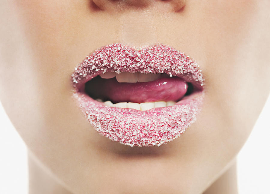 Close up of woman with pink lipstick licking sugar covered lips Photograph by Chris Ryan