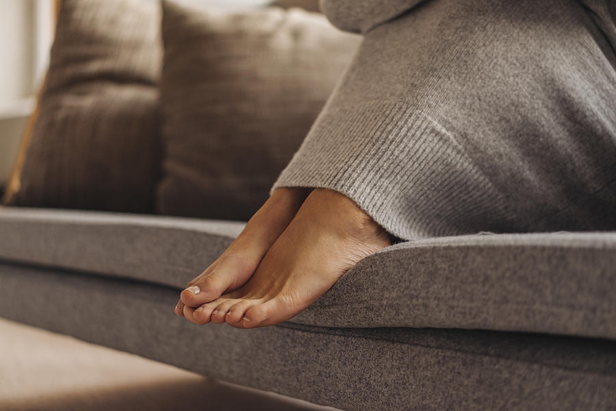 Close-up of womans feet sitting on couch Photograph by Westend61