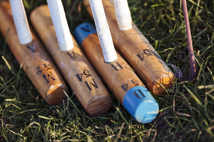 Close-up of wooden polo mallets on grassy field Photograph by Cavan Images