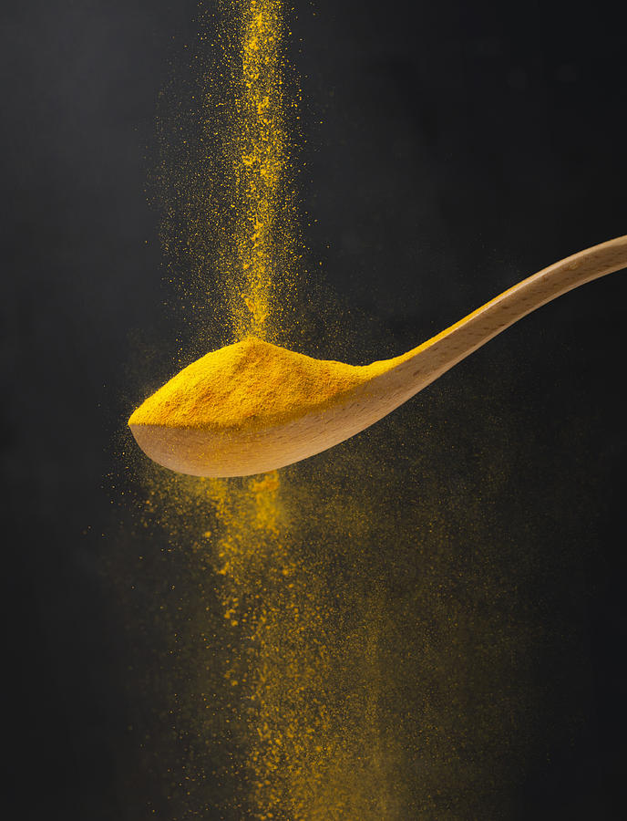 Close up view of turmeric powder in wooden spoon. Photograph by Twomeows