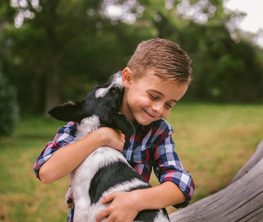 Closeup cute rascal boy gives his puppy a big hug Photograph by Wundervisuals