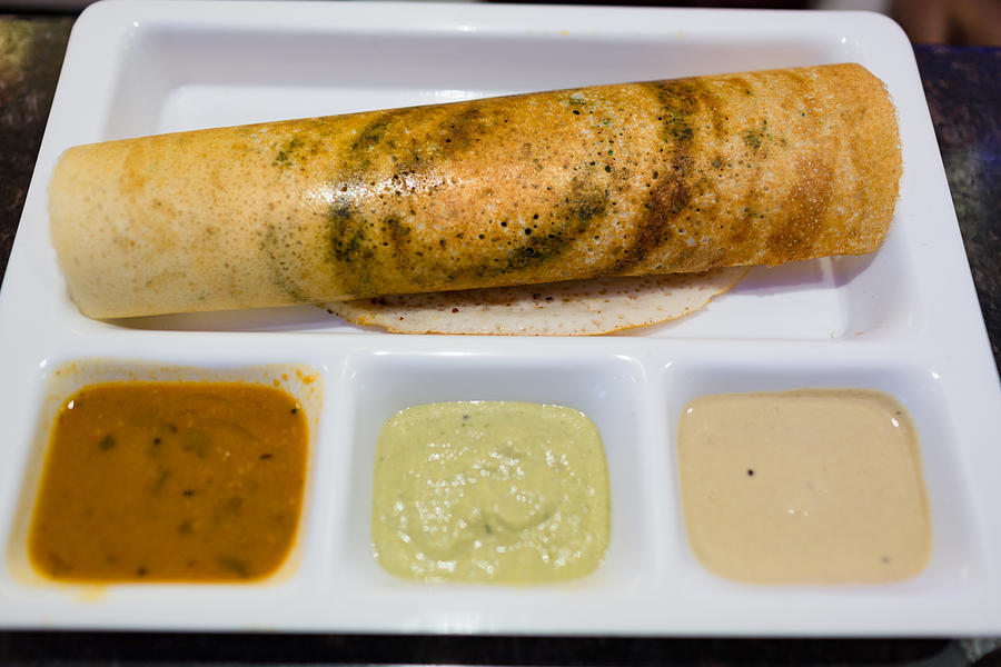 Closeup of crispy south indian masala dosa served with chutney and sambar on a white partitioned plate Photograph by Sanjay Borra