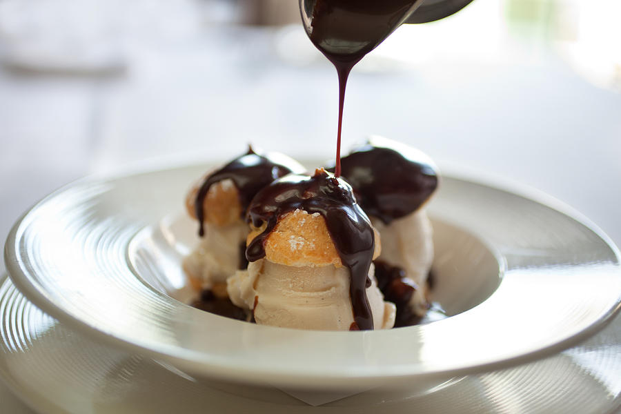 Closeup picture of profiteroles bathing in chocolate Photograph by Sf_foodphoto