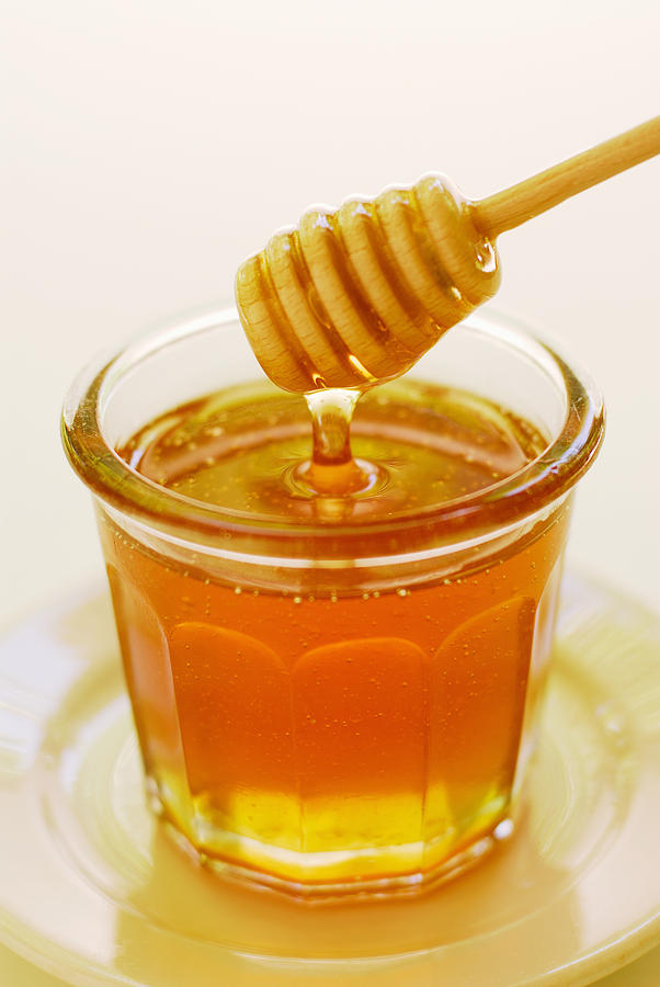 Clover honey in jam jar with dipper Photograph by Anthony-Masterson