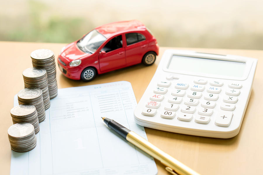 Coins stack in columns on saving book and car Photograph by Photobuay