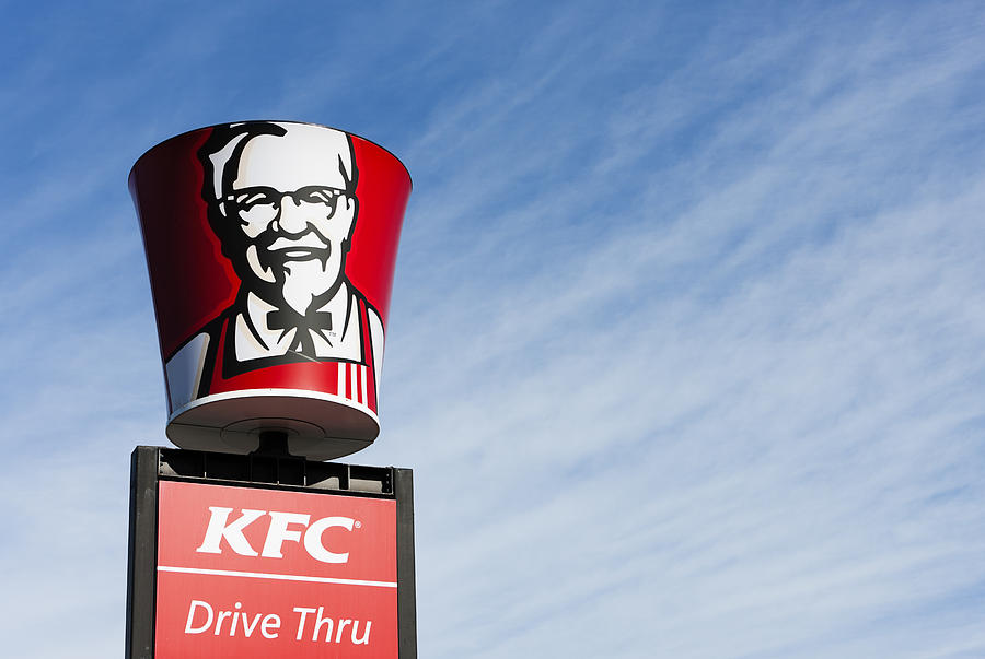 Colonel Sanders image on bucket-shaped sign above KFC franchise Photograph by RapidEye