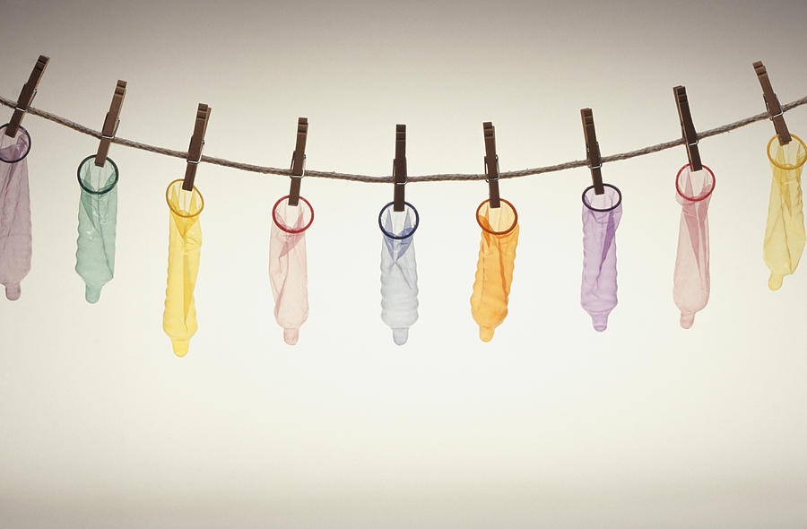 Condoms hanging on pegs from line Photograph by Keith Brofsky
