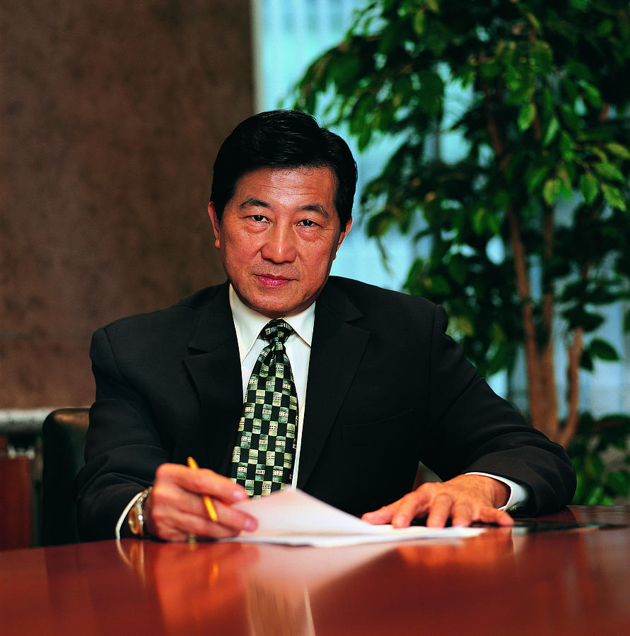 Confident Asian man at desk Photograph by Photodisc