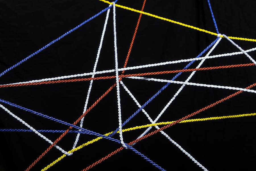 Connected threads in front of black background Photograph by Westend61