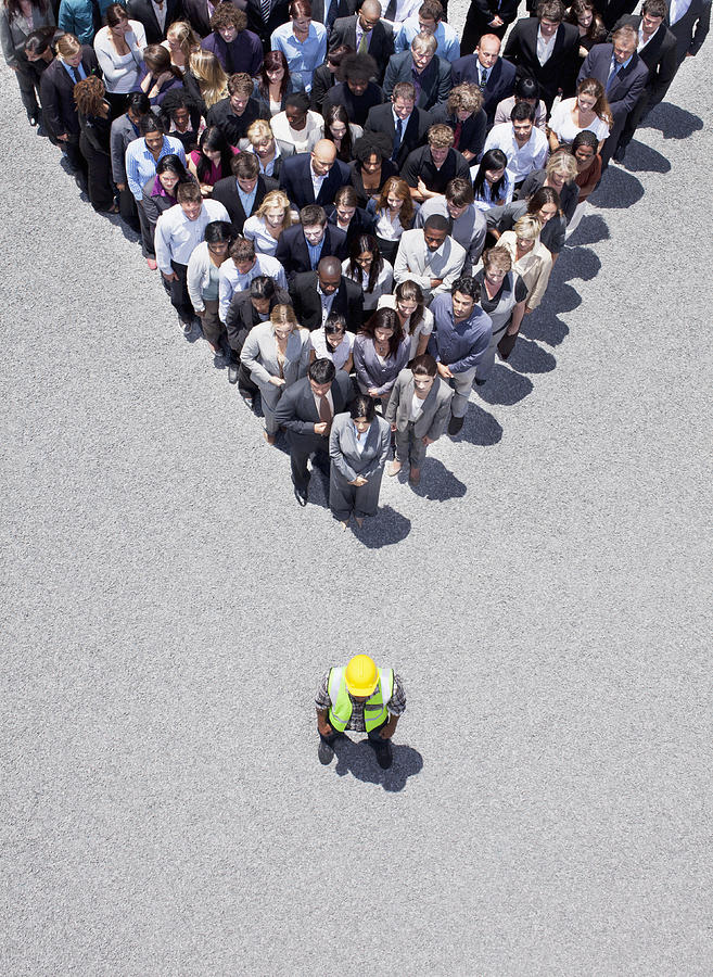 Construction worker at apex of pyramid formed by business people Photograph by Martin Barraud