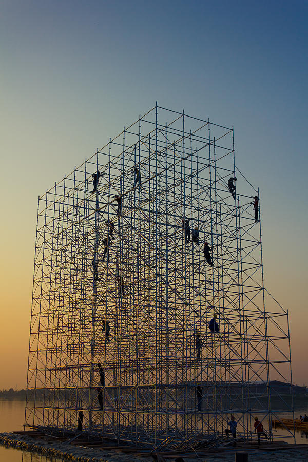 Construction workers on scaffold at sunset Photograph by Eastimages