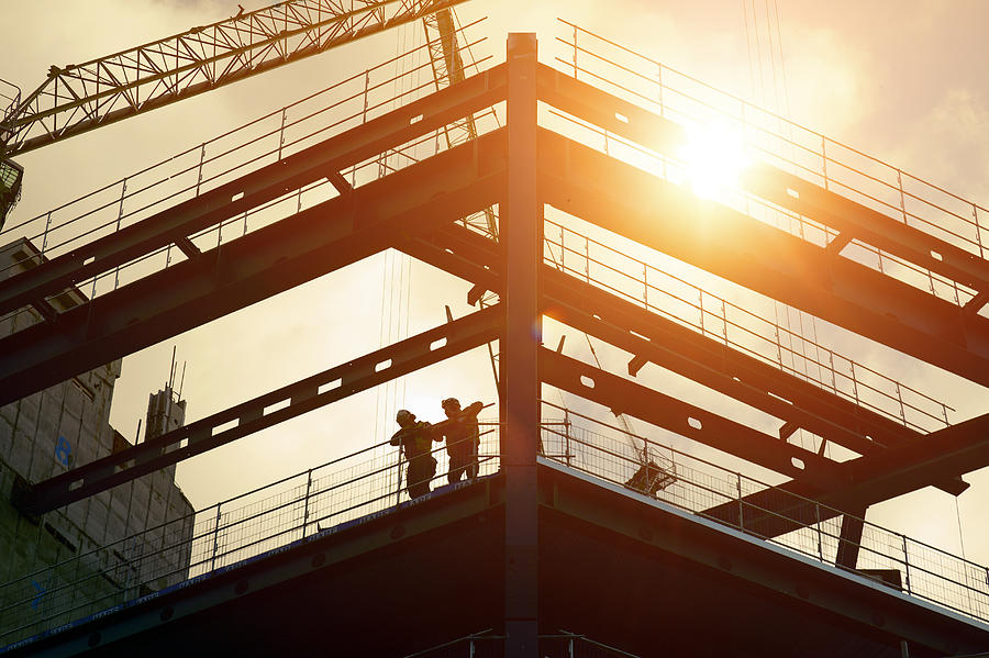 Construction workers silhouetted against the sun Photograph by Ezra Bailey