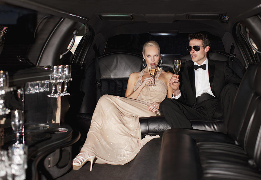 Couple drinking champagne in limo Photograph by Tom Merton